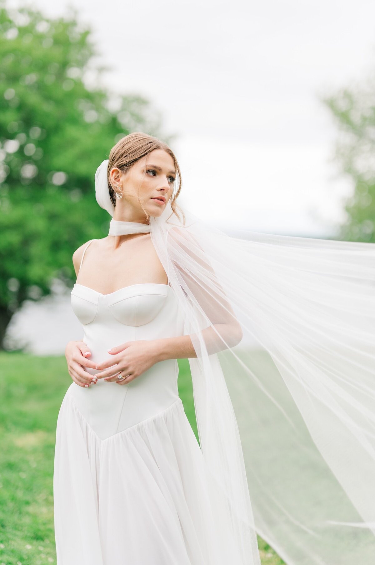 A bride with a veil flying in the wind peers over her shoulder. 
