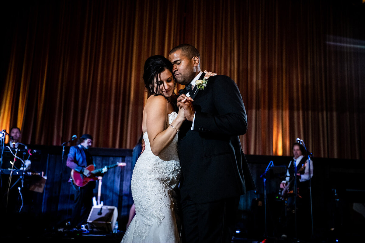 San Francisco Bay Area wedding photographer captures tender first dance moment with bride and groom embracing while live band performs at Estate Yountville in Napa Valley