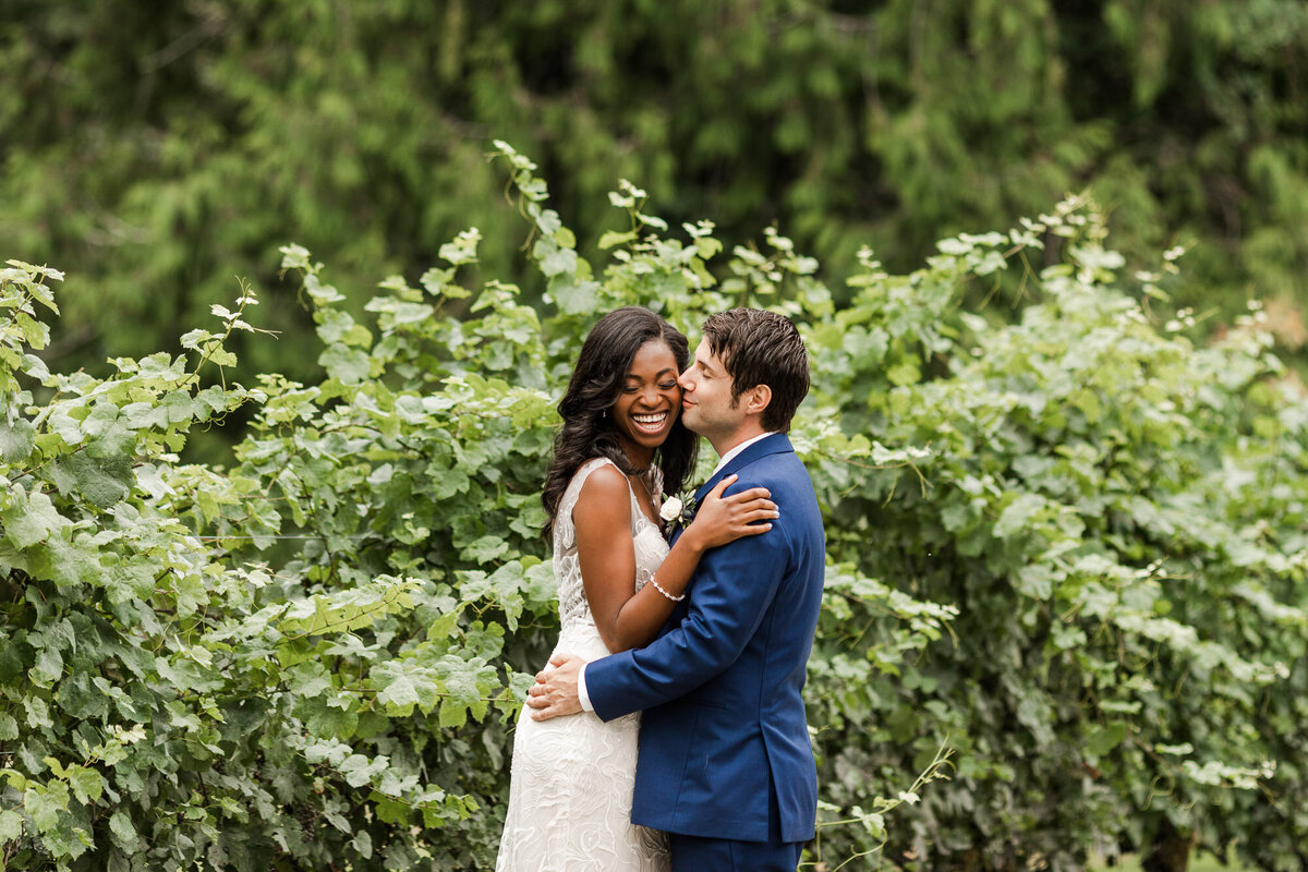 Bride-and-groom-kiss-on-wedding-day-in-vineyard-in-Green-Gates-at-Flowing-Lake-wedding-venue-Snohomish-WA-photo-by-Joanna-Monger-Photography