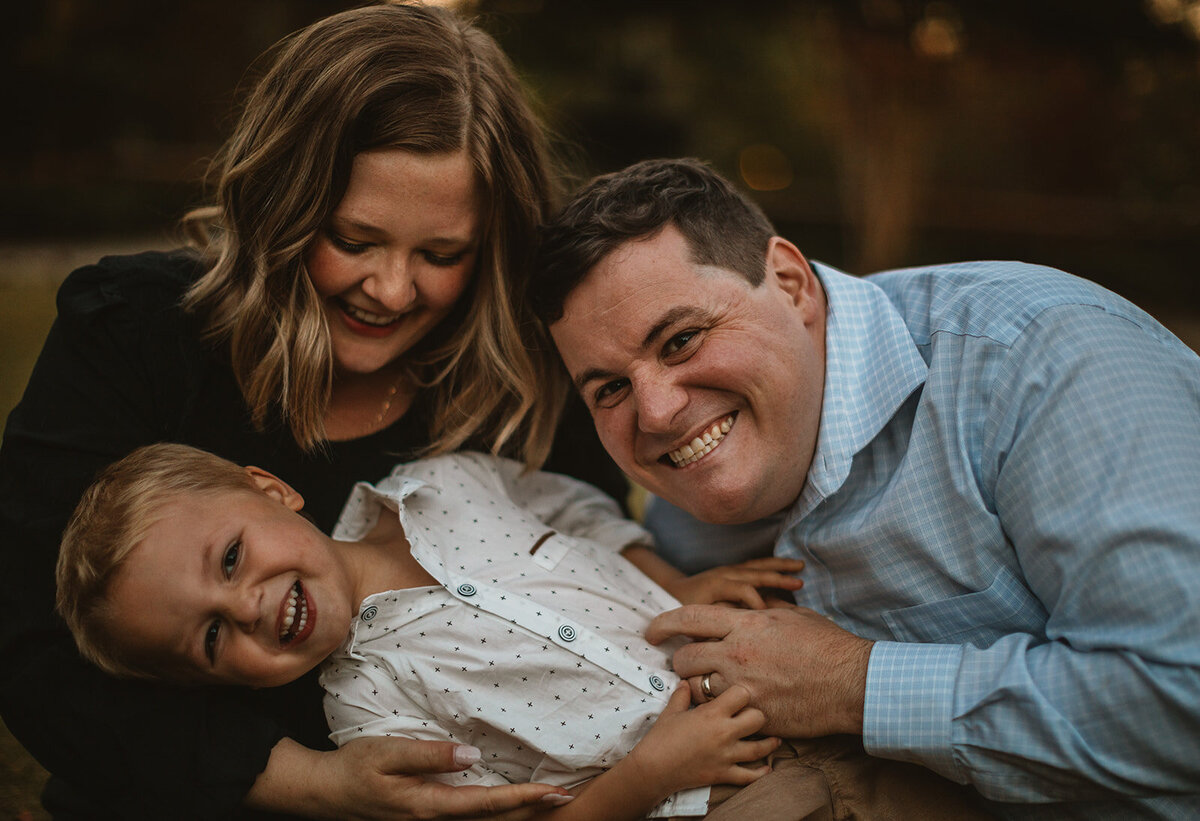 parents cuddle their son