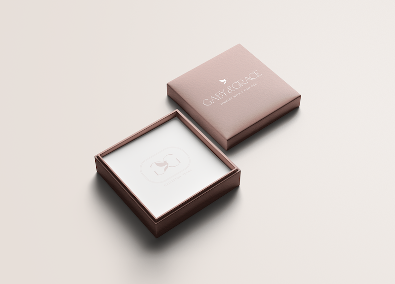 Sophisticated rose-toned jewelry box with the Gaby & Grace logo embossed on the lid, showcasing elegant and thoughtful packaging for their e-commerce and retail products.