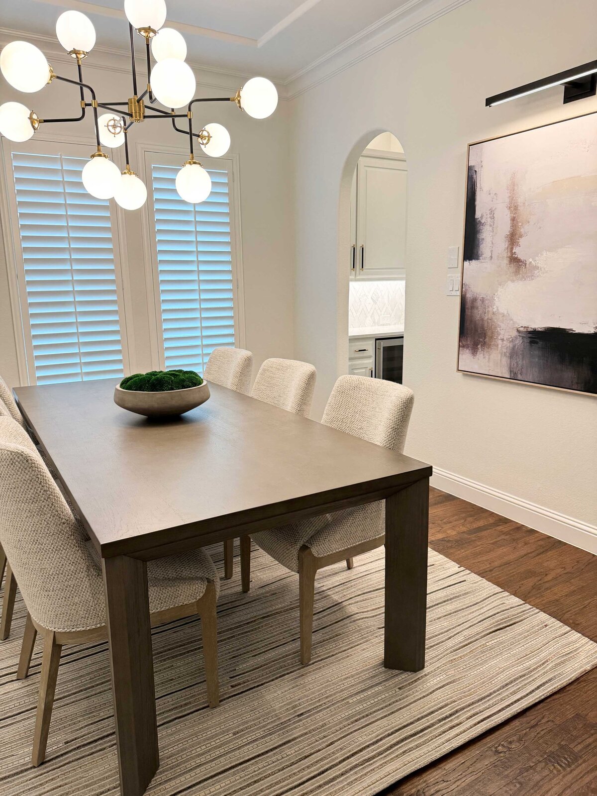 Home interior design contractor service for a dining room featuring an elegant ceiling lamp and brown artwork, creating a sophisticated atmosphere.