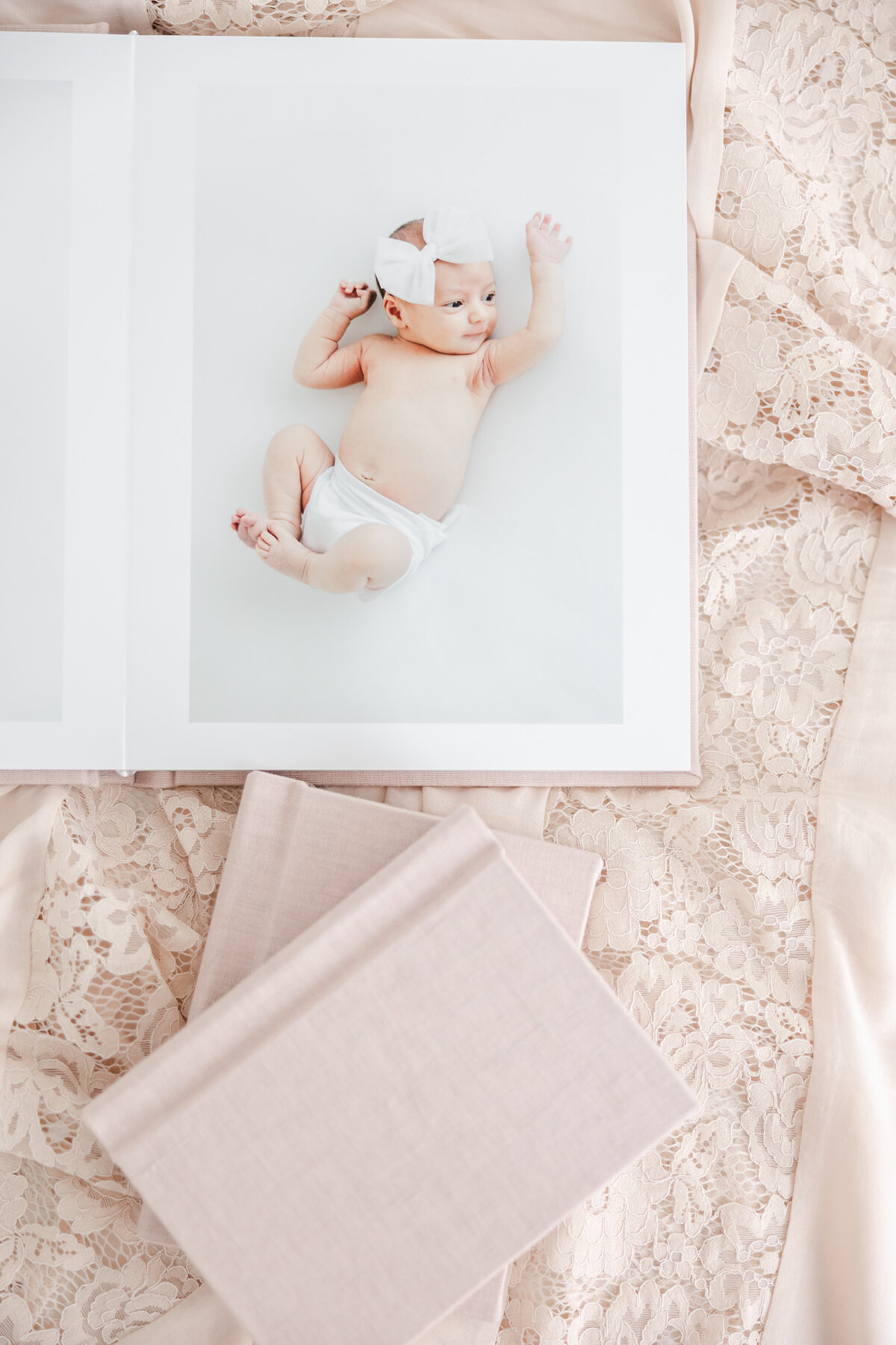 Family photo album open to spread of newborn baby girl wearing white bow