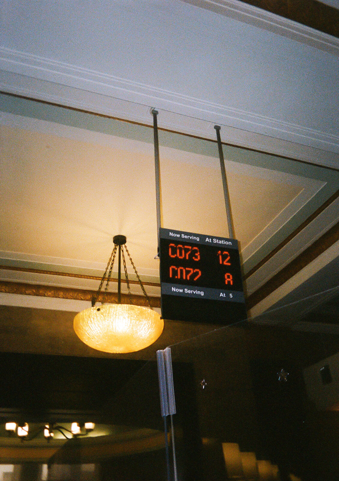 Film photo of the number board inside New York City Hall showing couples waiting for their marriage license appointments, captured during Japna and Chris’s elopement by NYC wedding photographer Perry Hancock.