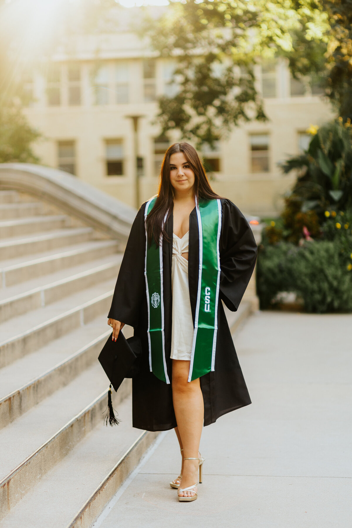 A proud Colorado State University graduate poses for a portrait in front of the Administration Building in Fort Collins, Colorado.