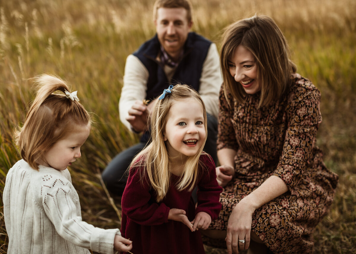 family plays in a field at sunset for photos