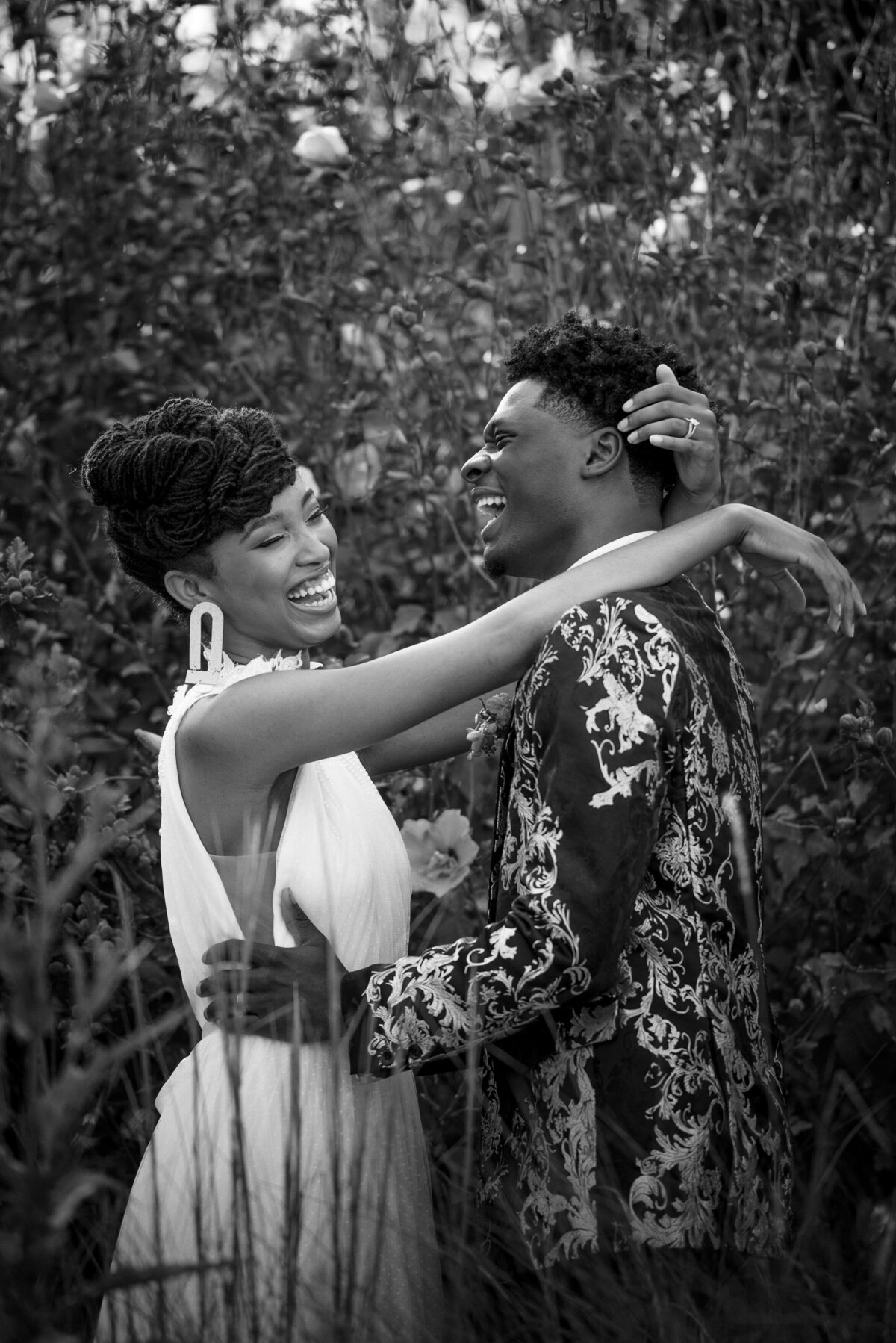 Black bride and groom laughing in greenery at North Corner Haven by Charlotte wedding photographers DeLong Photography
