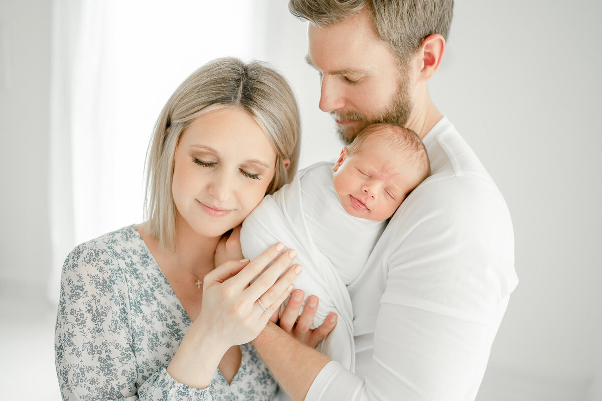 New parents hold their baby In Kristie Lloyd’s Nashville newborn photographer studio