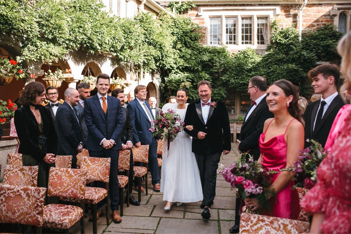 Bride walsk up the aisle with Dad to a sea of smiles