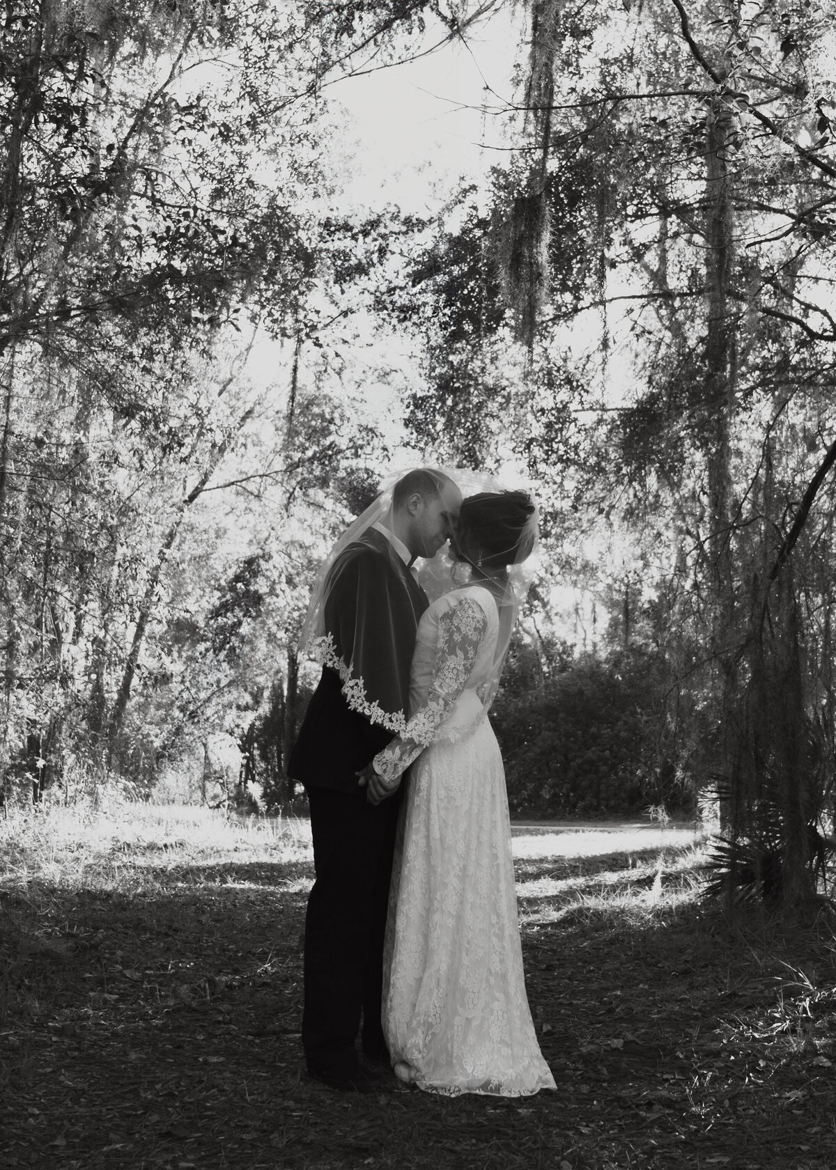 Bride and groom surrounded by nature  with veil over both Florida venue