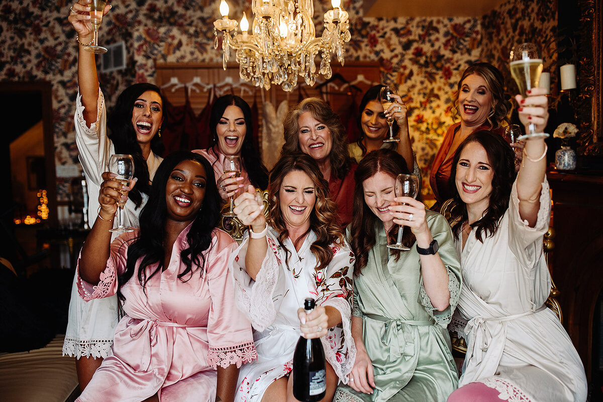 Bridesmaids in satin robes celebrate with champagne on the wedding day.
