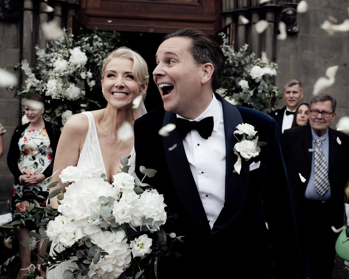 Bride and groom celebrate with guests underneath a storm of confetti