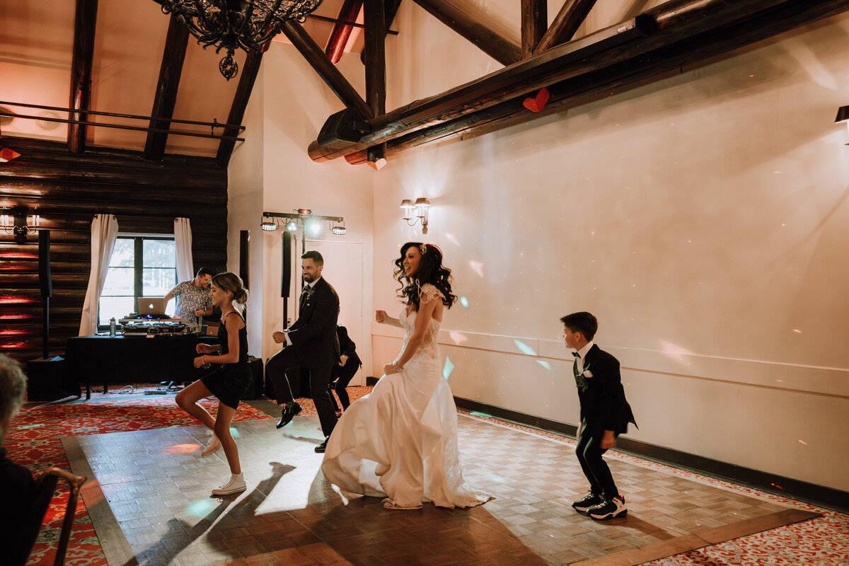 A candid shot of the groom and bride and their children with a dance performance for the guests