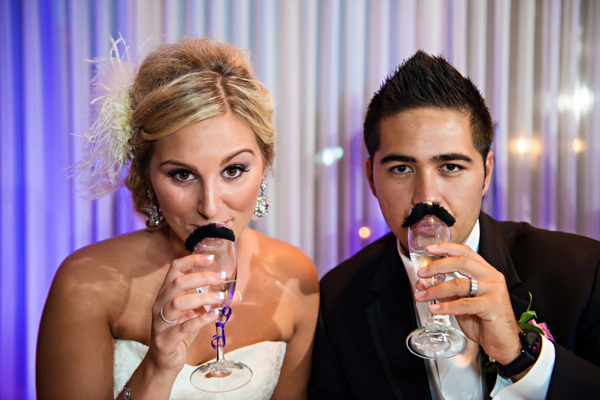 A bride and groom drink champagne from glasses with mustaches on them at their Northampton Valley Country Club Wedding.