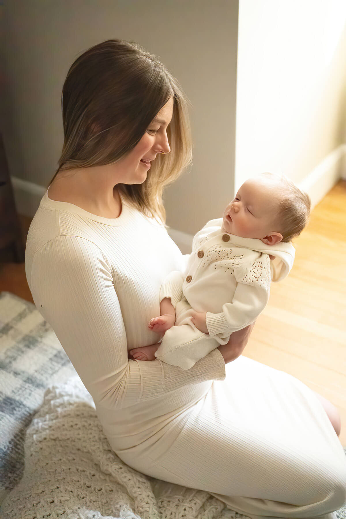 A mother looks lovingly at her newborn as she sits on the nursery floor of her Wakefield home.