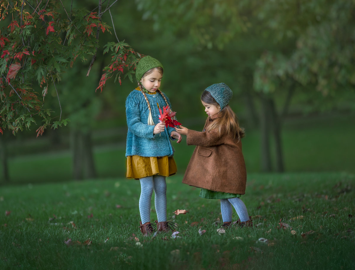 Two sisters laughing and tossing autumn leaves during a playful outdoor fall session – Ottawa children’s photographer Sonia Gourlie