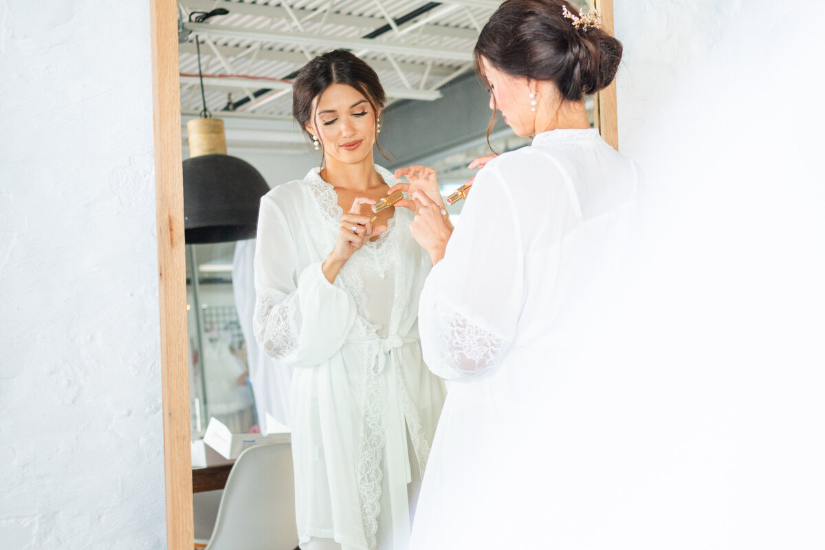 bride getting ready in the mirror during her wedding at the Atrium in Wilmington, NC