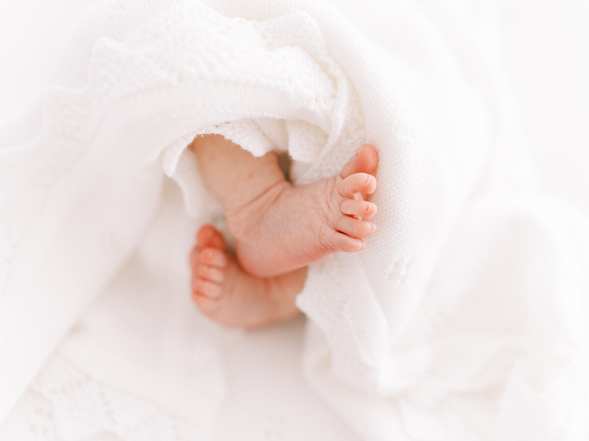 close up of newborn baby's feet wrapped up in a white blanket
