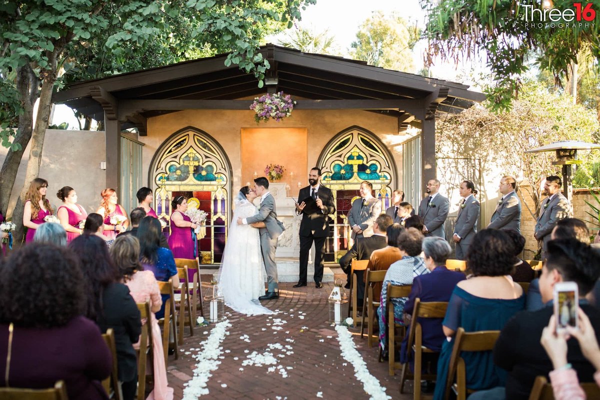 Newly married couple share their first kiss at the altar at an outdoor wedding site