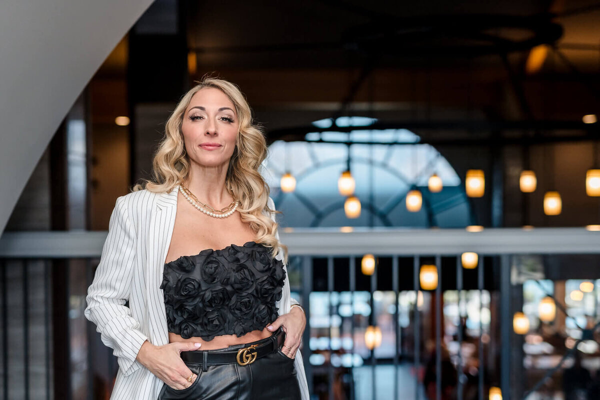 Businesswoman posing in striped blazer and leather pants inside a modern Kelowna hotel during brand shoot.
