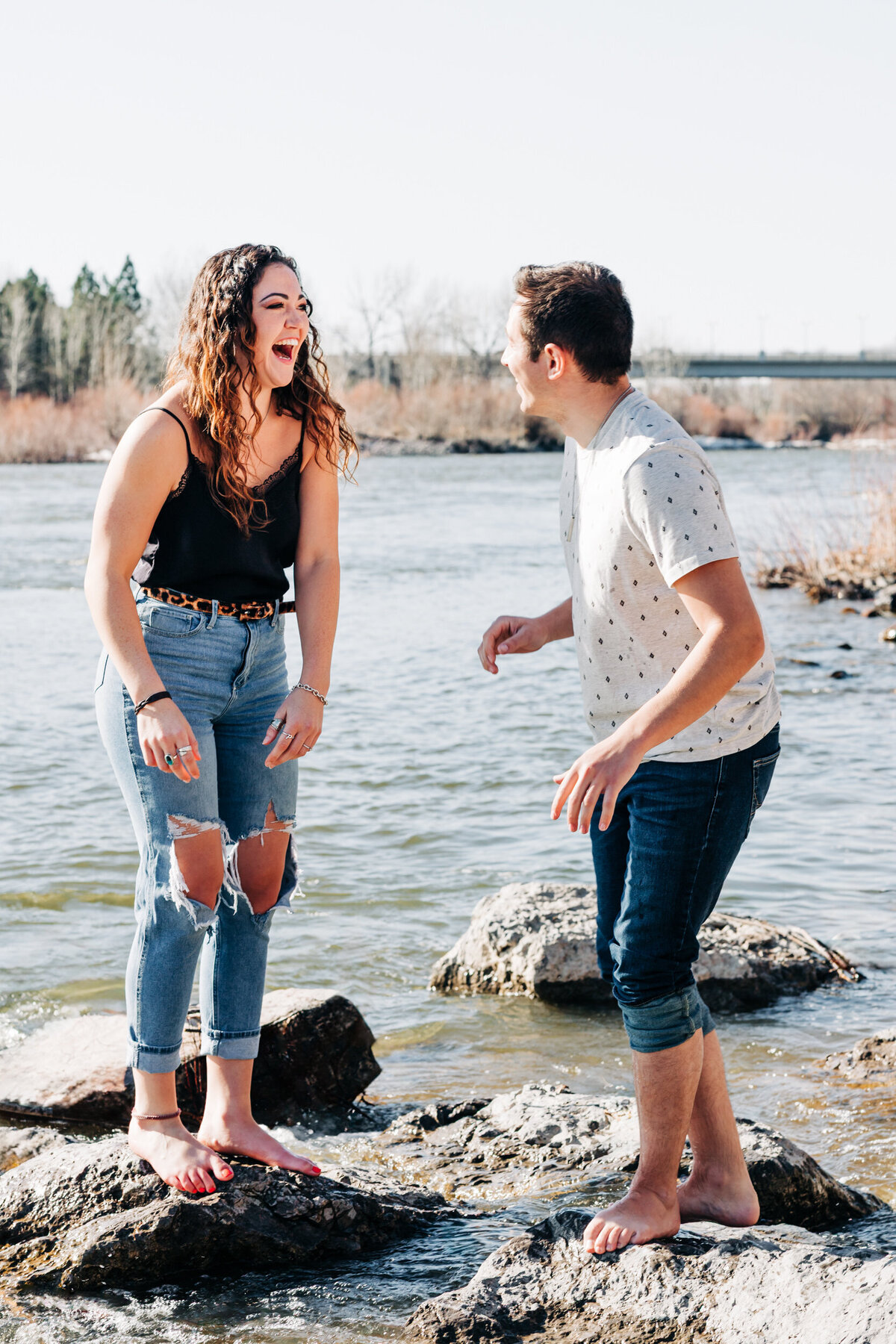 Engagement photo couple walking on rocks in Clark Fork River, Missoula