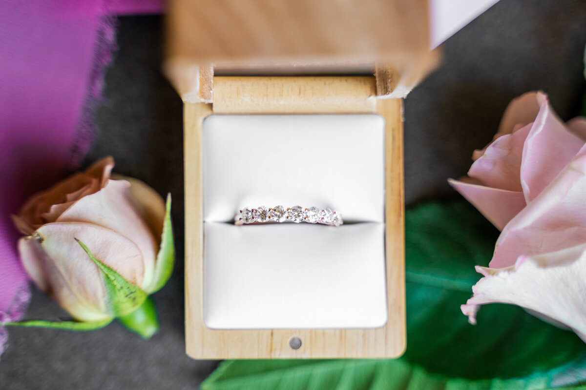 The groom's wedding band in a ring box with pink roses on either side at a wedding at The Terrace in Columbus, Ohio.