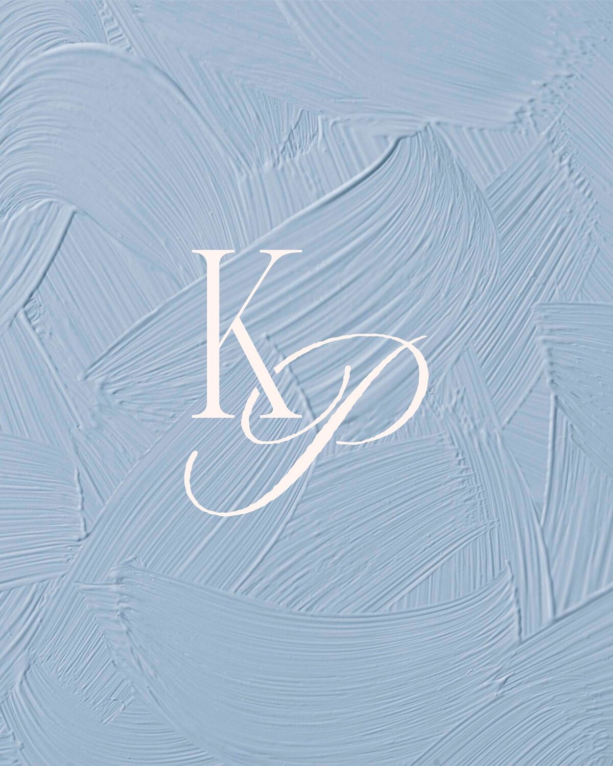 A professional, high-resolution image of the monogram "KP" logo for Korianne Paints. The elegant, intertwined letters are set against a background of artistic dusty blue brush strokes, reflecting her romantic painting style.