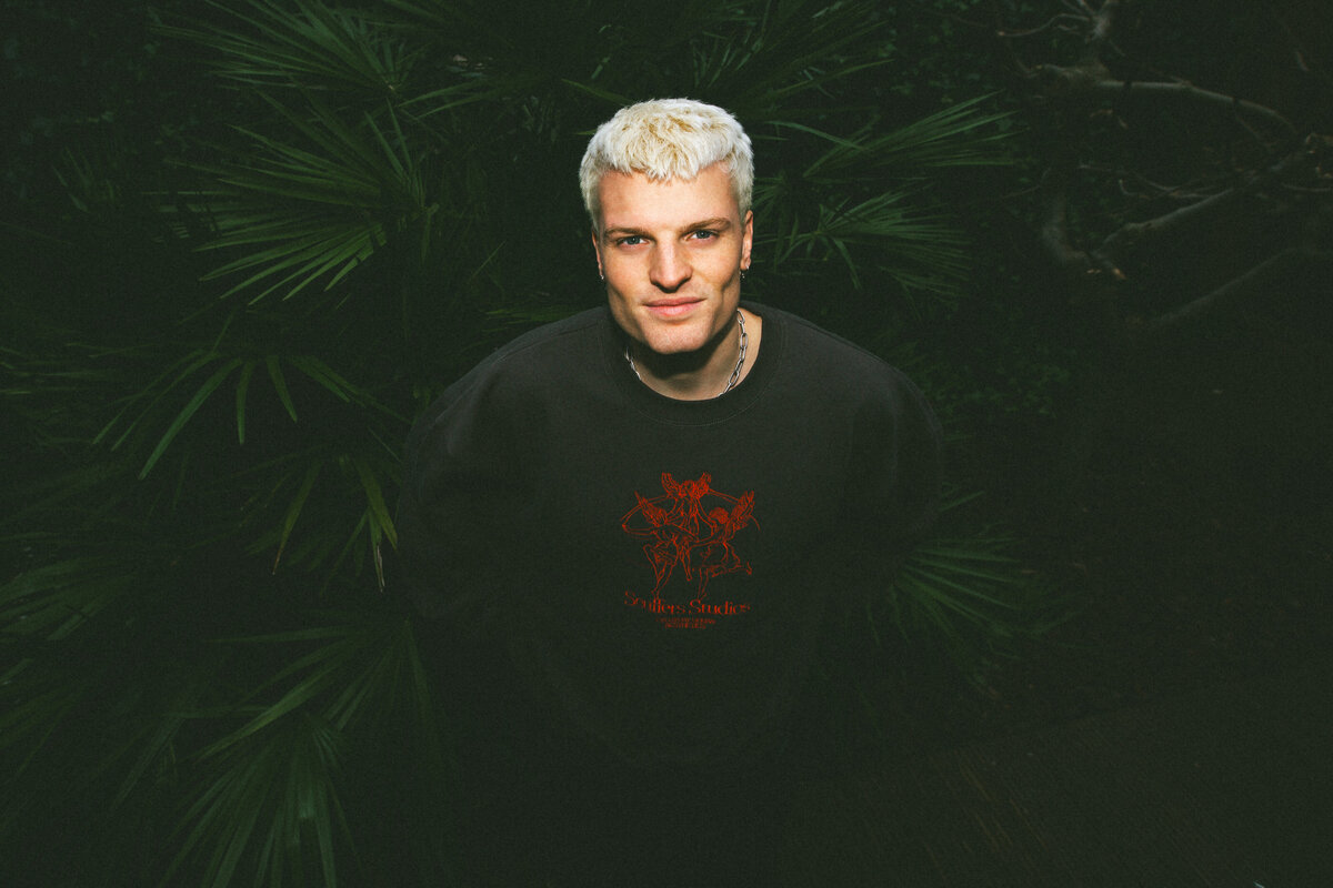 Bo Eppink photographs Sam Hofman against a lush green backdrop, emphasizing the contrast between his look and nature.
