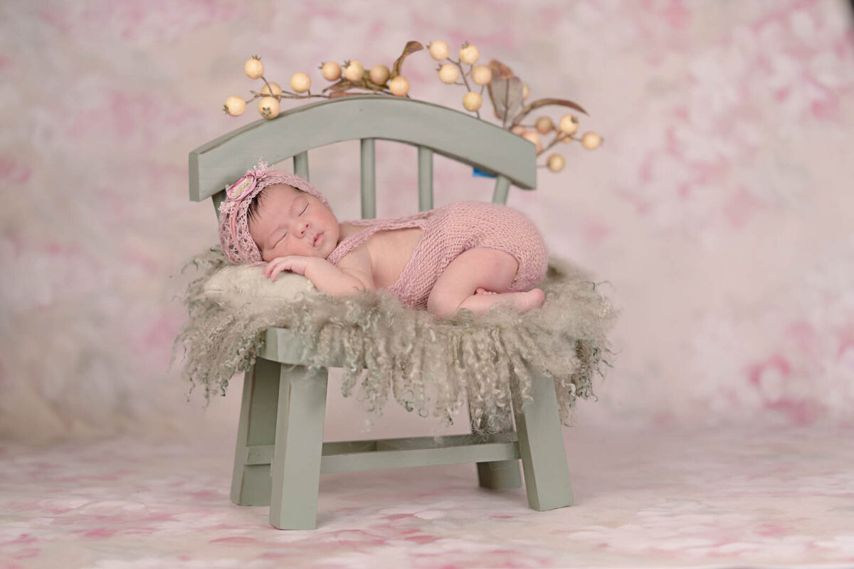 Newborn girl sleeping on a mini-chair