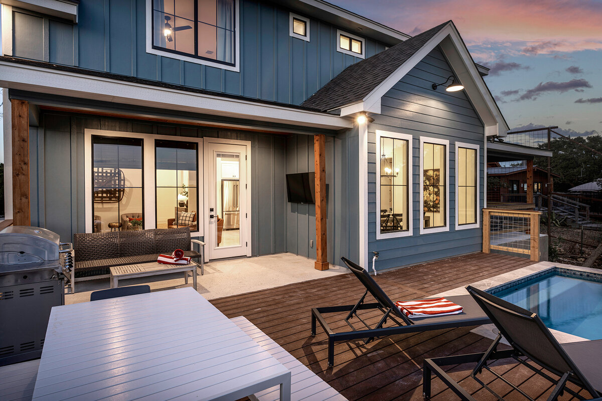 blue board and batten house with wood deck and poolside seating