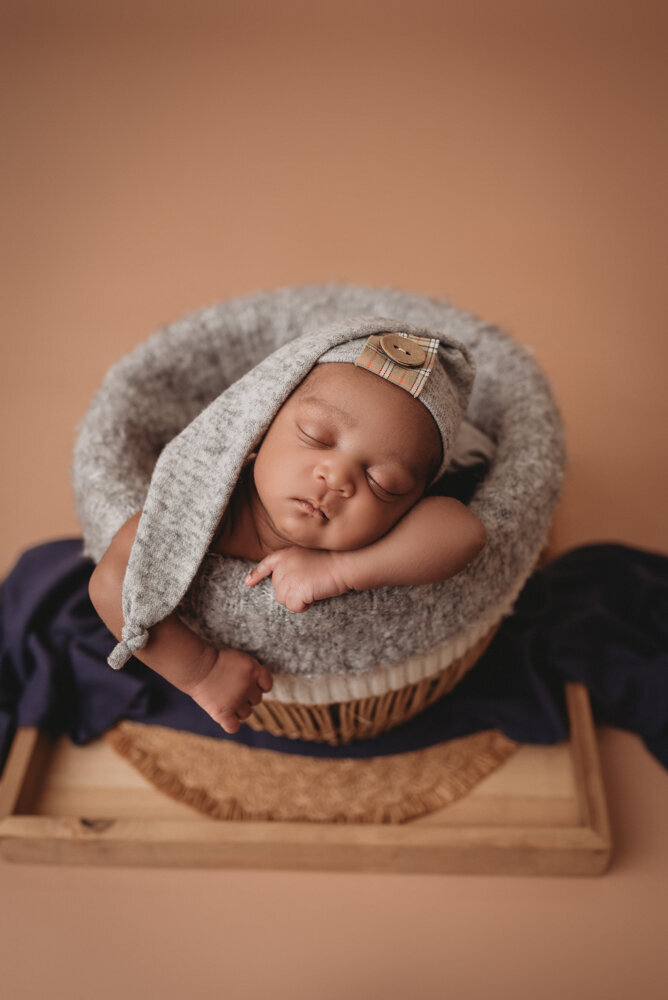 Newborn photos with Atlanta, Georgia newborn photographer of sleeping baby boy with hands under chin in a basket