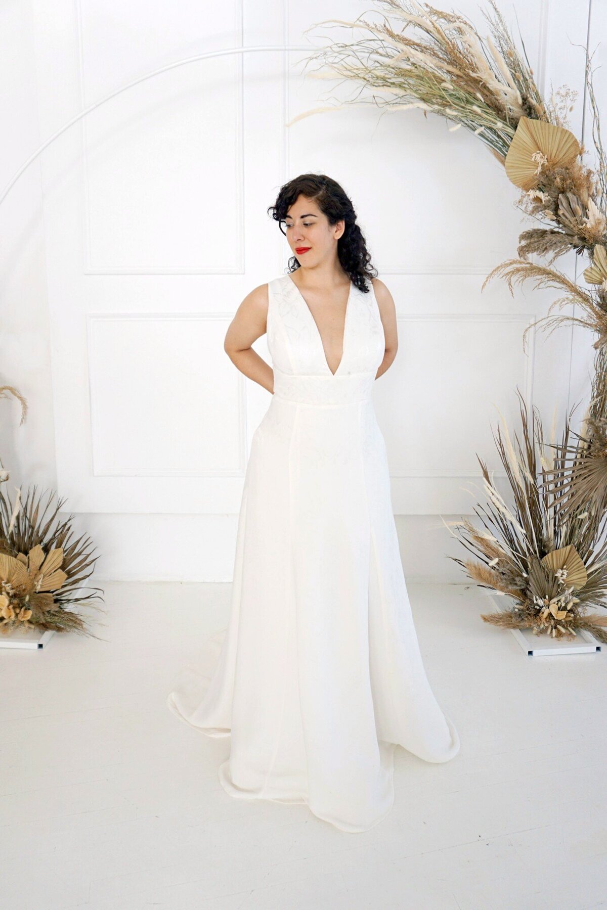 The Sol wedding dress style showcases the modified a-line skirt and v-neck bodice. It is made in a floral jacquard crepe.