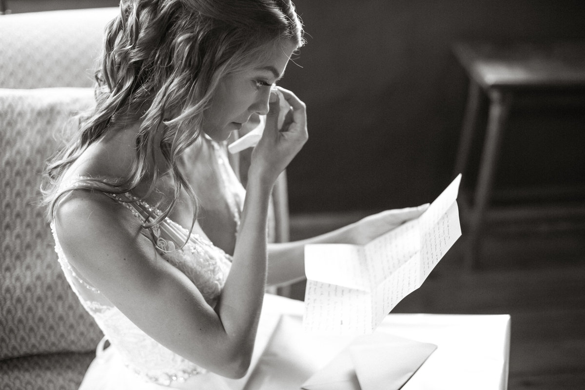 Bride reading a letter from her groom, before the wedding ceremony at Grace Winery.