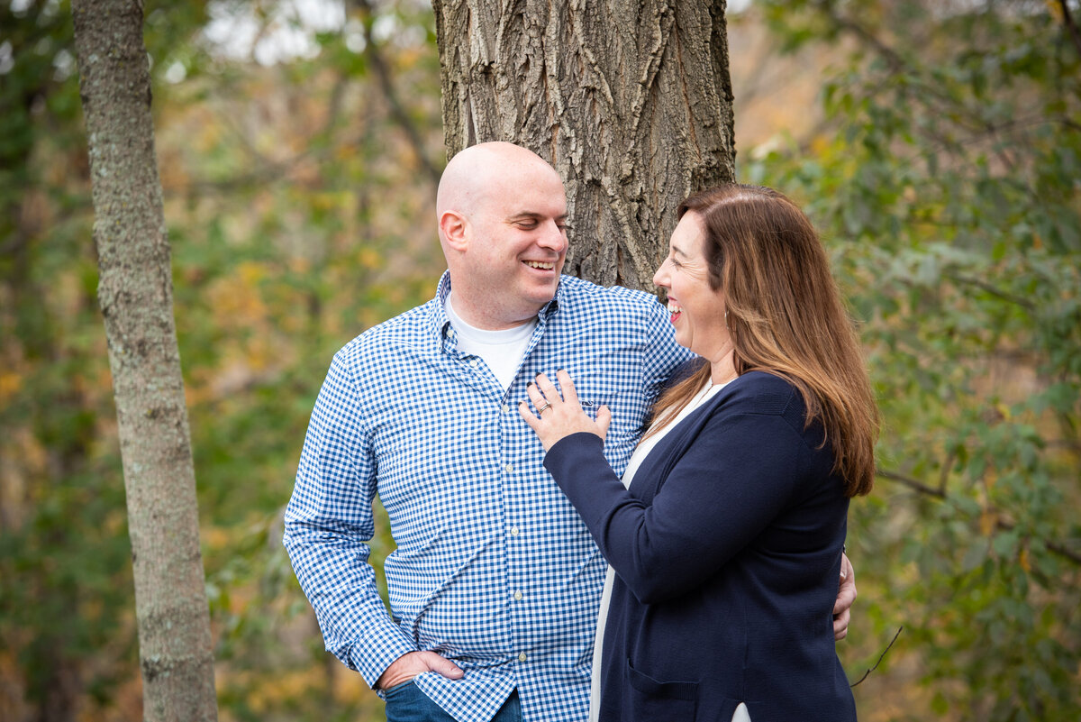 A couple with their arms around them next to a tree