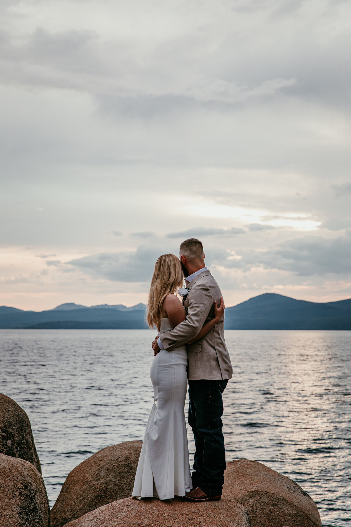 Couple embracing on the rocks at Sand Harbor, Lake Tahoe, during their sunset elopement.