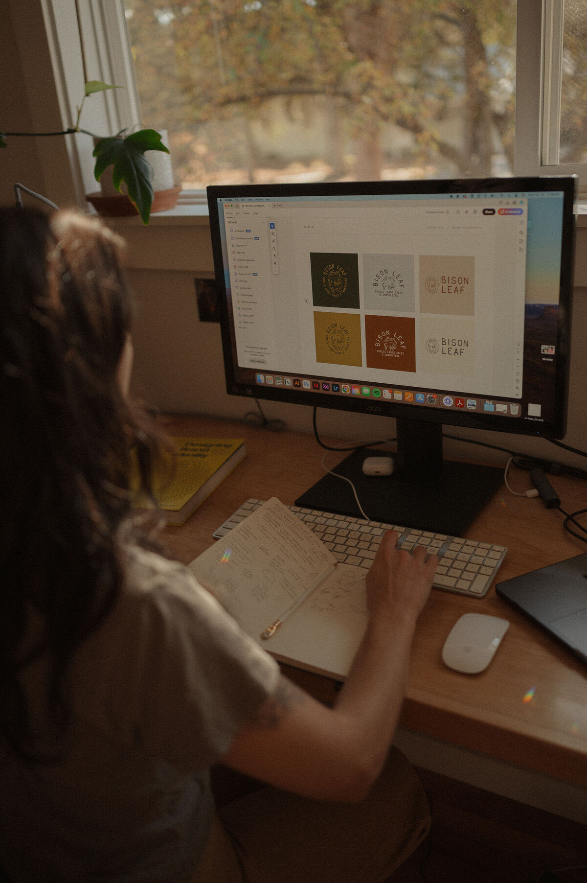 graphic designer works at her computer while reading a brand book during an at home photoshoot in Oregon