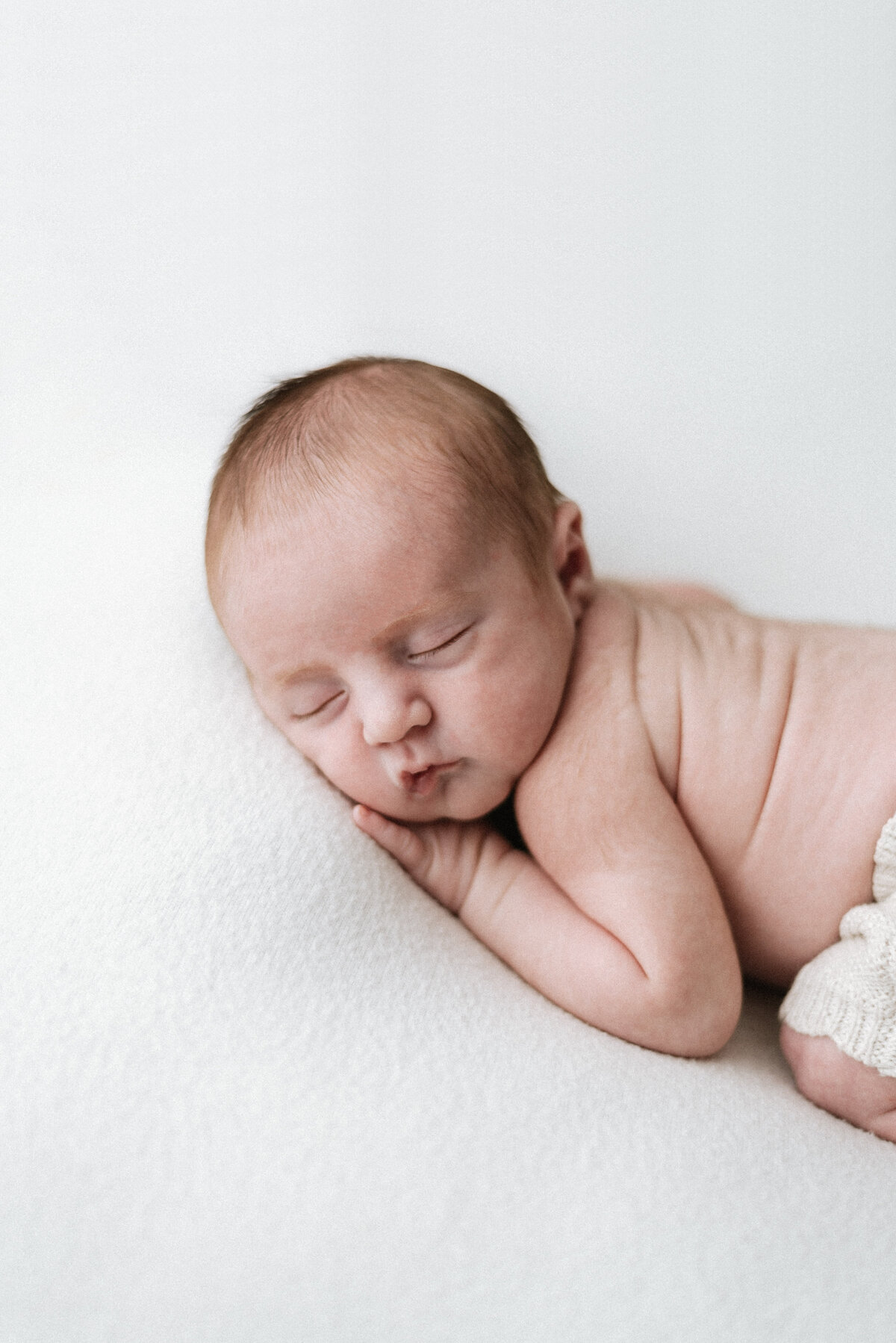 newborn boy sleeping on his front at newborn photoshoot in Billingshurst