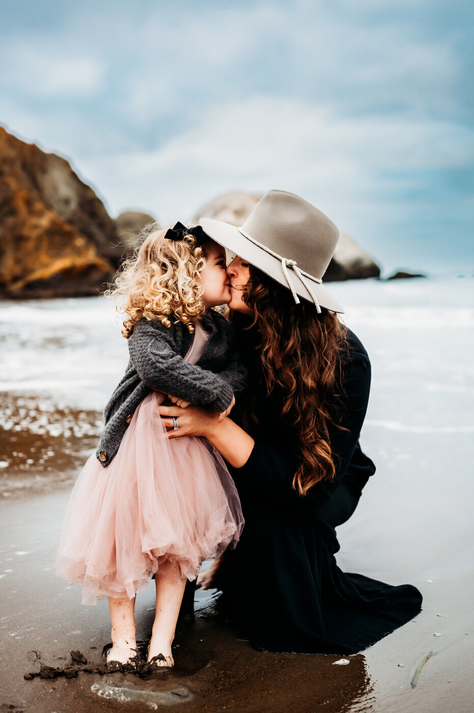 mama and daughter share a kiss down by the water in San Francisco