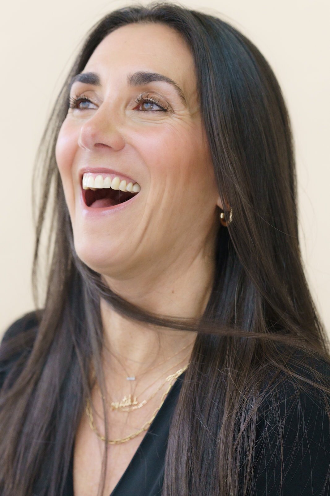 Young woman with long, dark hair laughing while taking a headshot photo