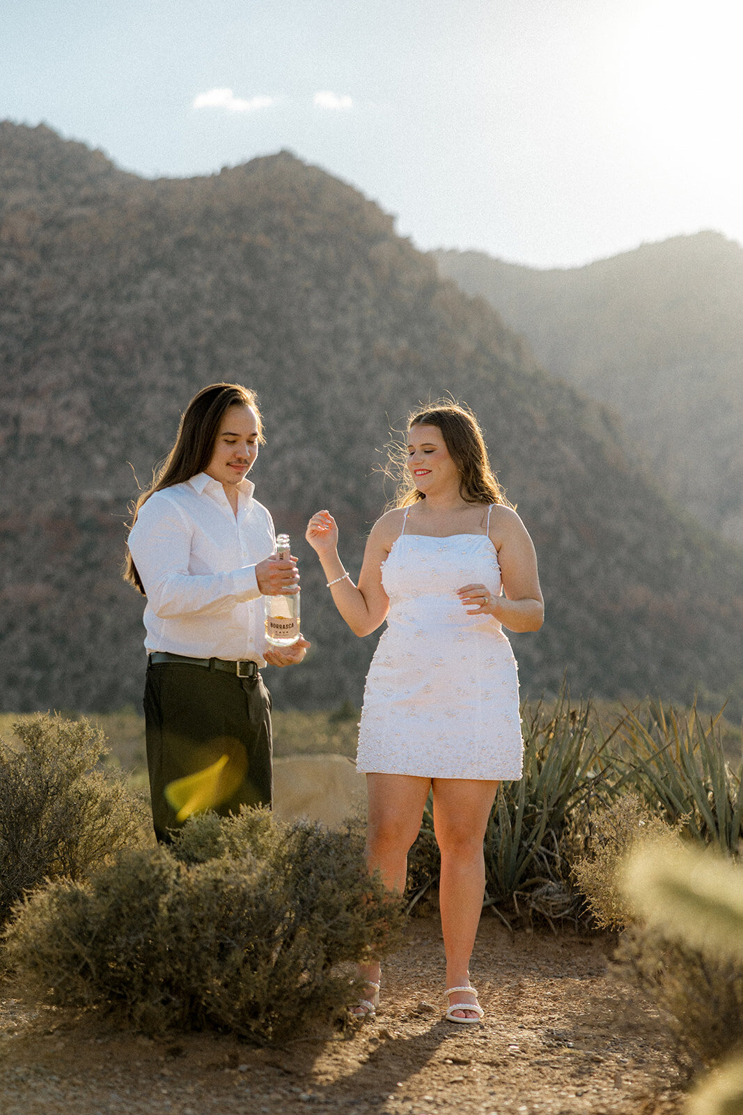 Engaged couple laughing with Nevada mountains in back