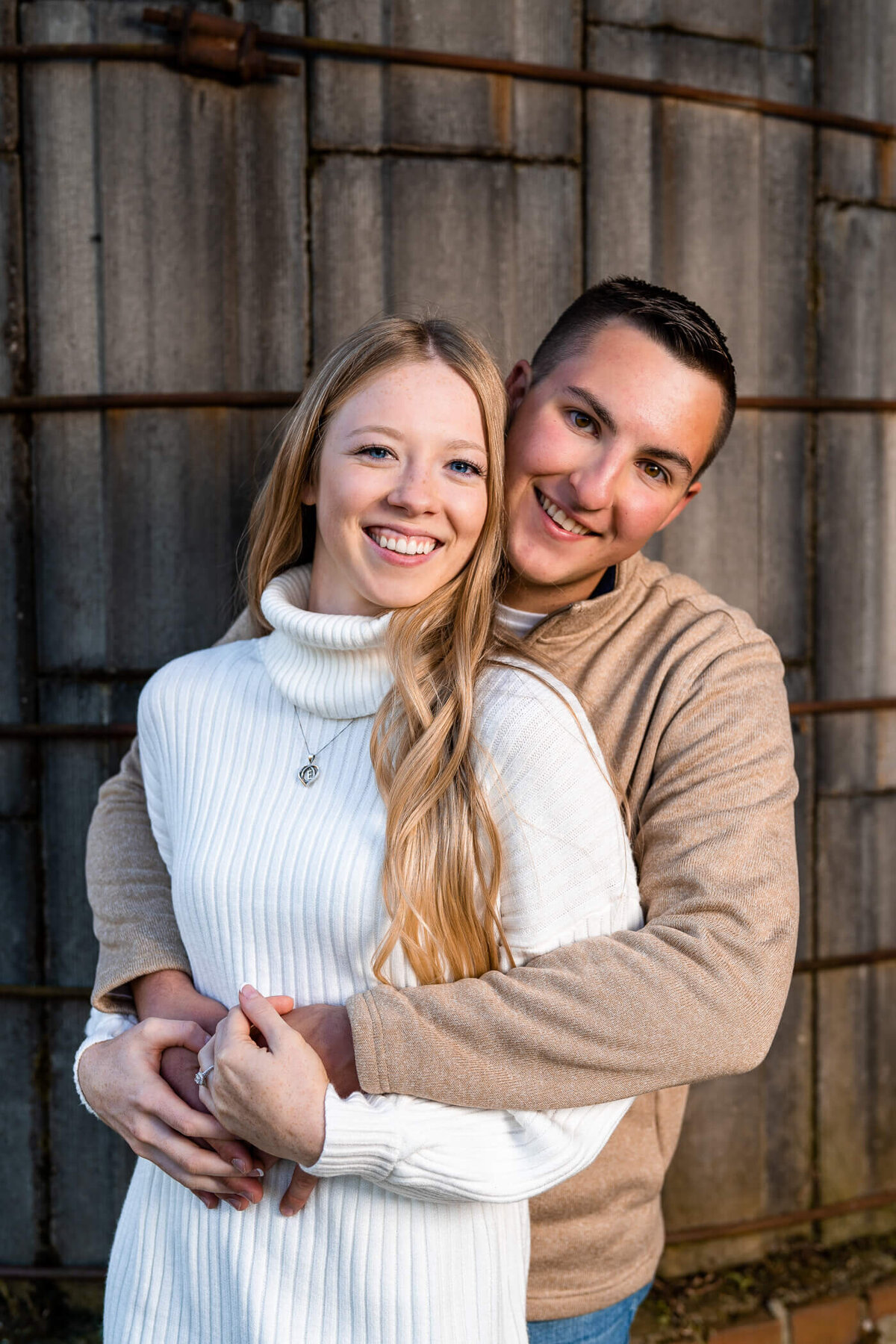 Pittsburgh engagement photography of a couple with their arms wrapped around each other in front of a silo during an engagement session near beaver county PA