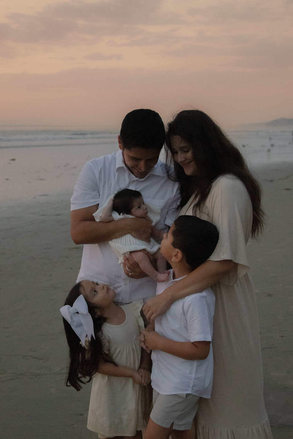 Family gathered together on the beach at dusk, looking affectionately at each other