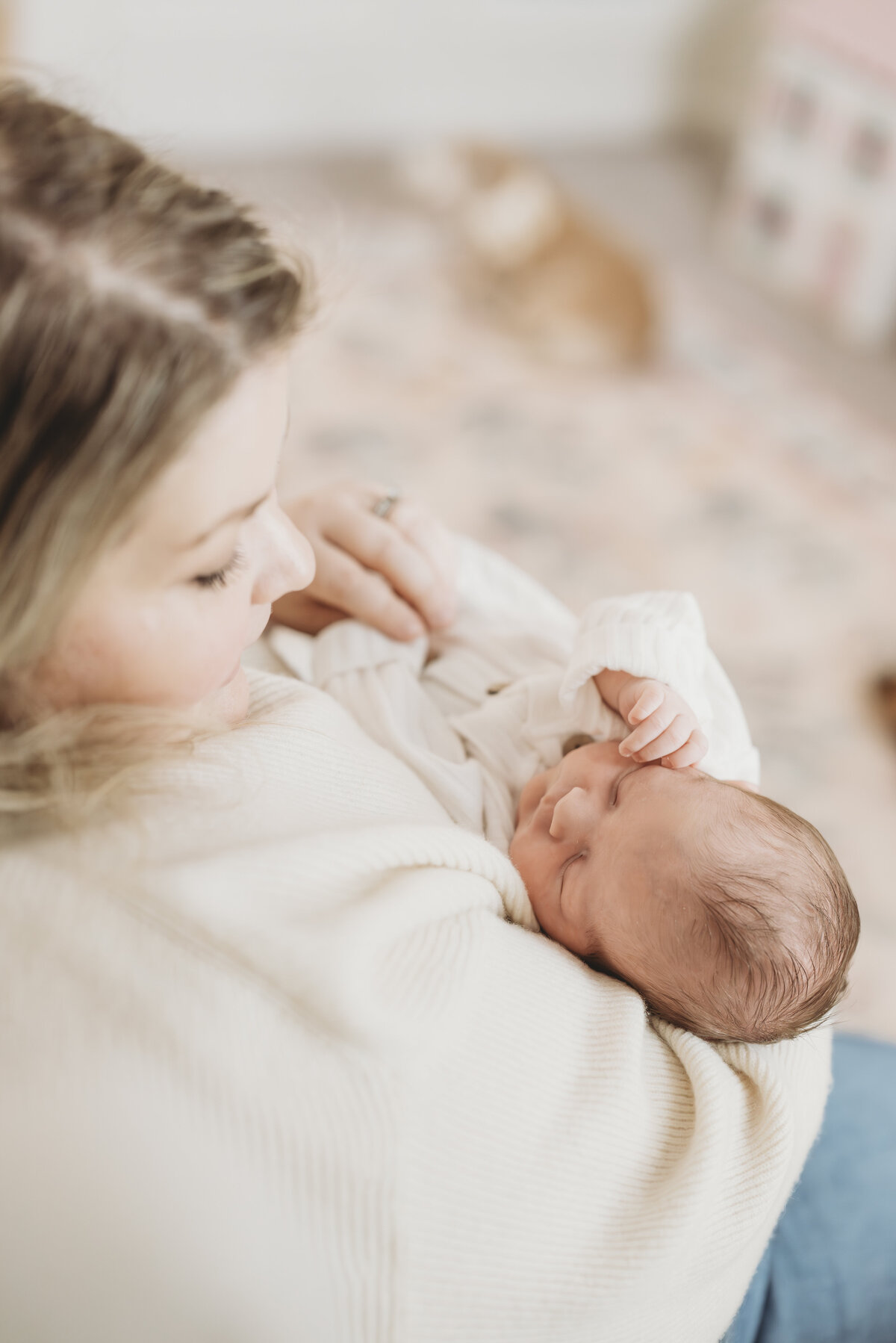 Mother holding her baby and smiling down lovingly during a relaxed in-home newborn session.