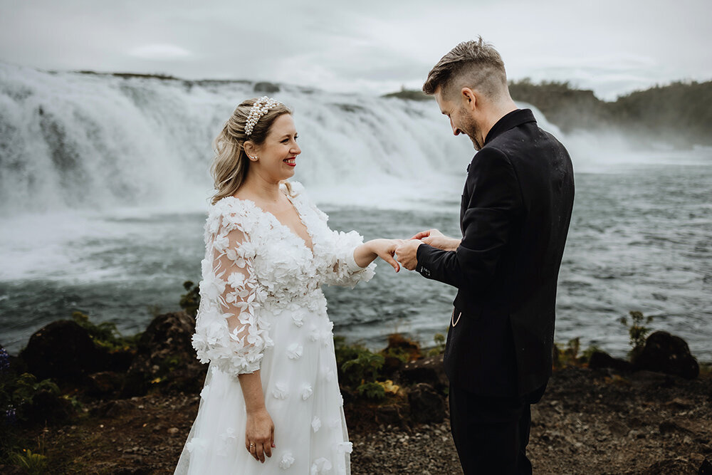 Canadian couple is exchanging rings in front is a waterfall in Iceland