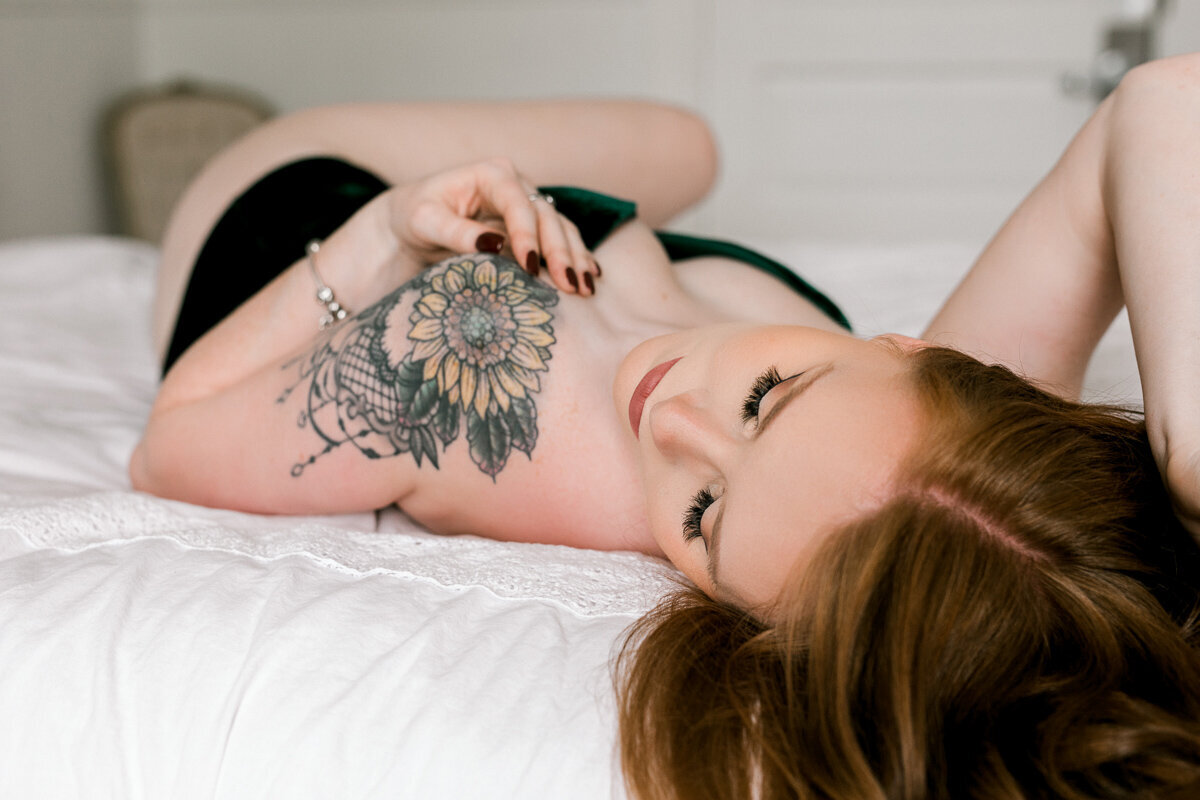 woman laying on bed with sunflower tattoo