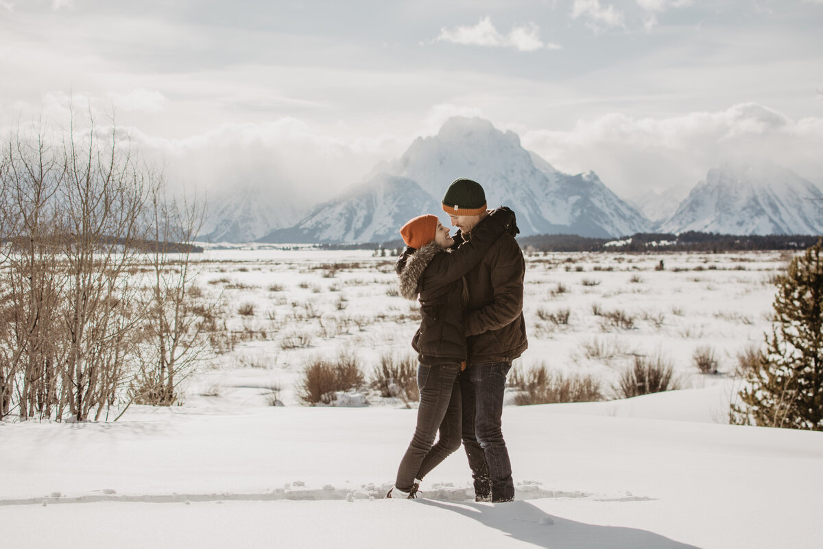 womans arms are around her fiances neck as she looks into his eyes for their winter engagement session in Jackson Hole