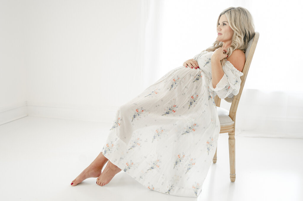 Pregnant woman reclines in a chair in a see translucent dress by Nashville maternity photographer Kristie Lloyd