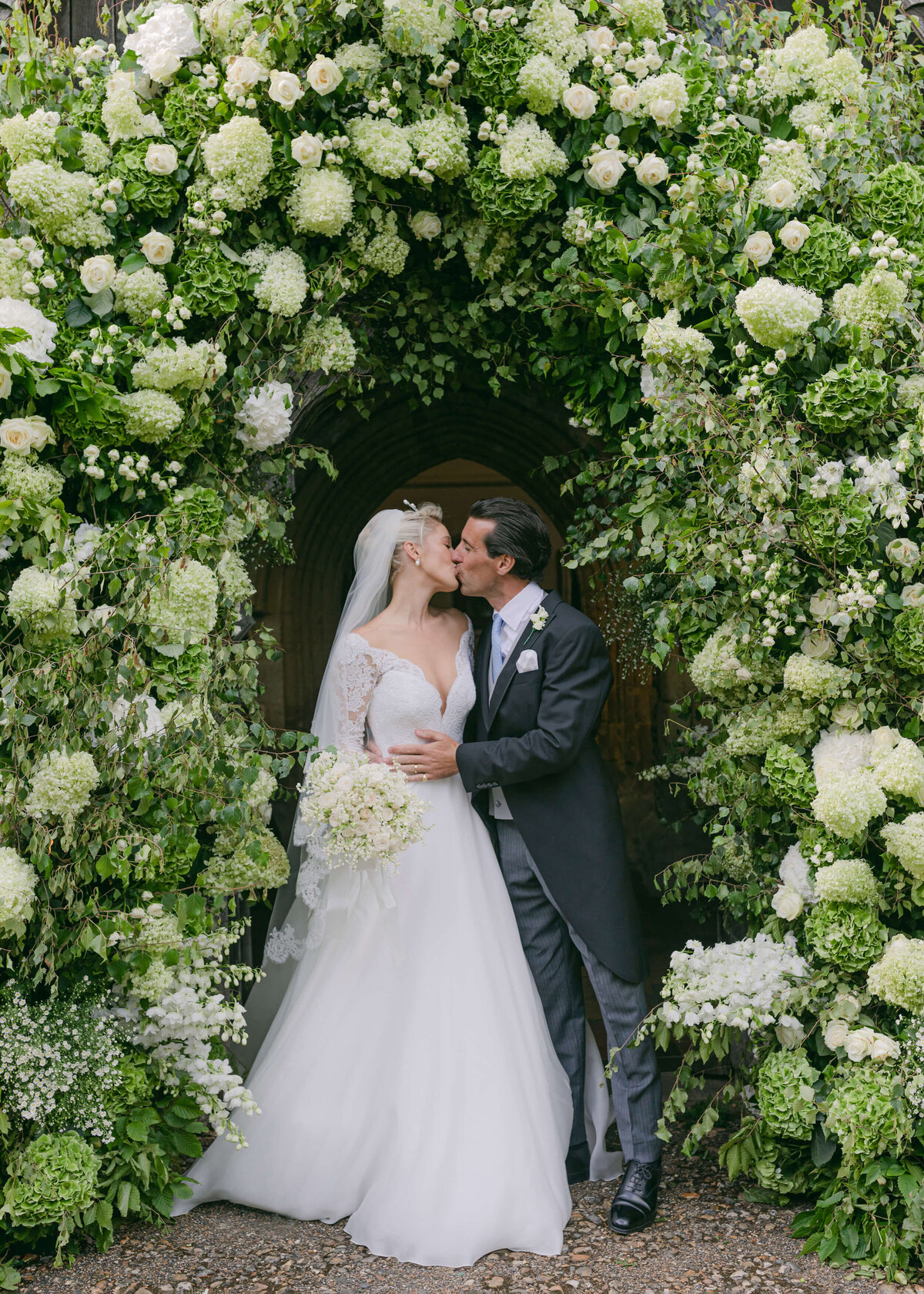 chloe-winstanley-weddings-hambleden-church-flower-arch-kiss-bride-groom