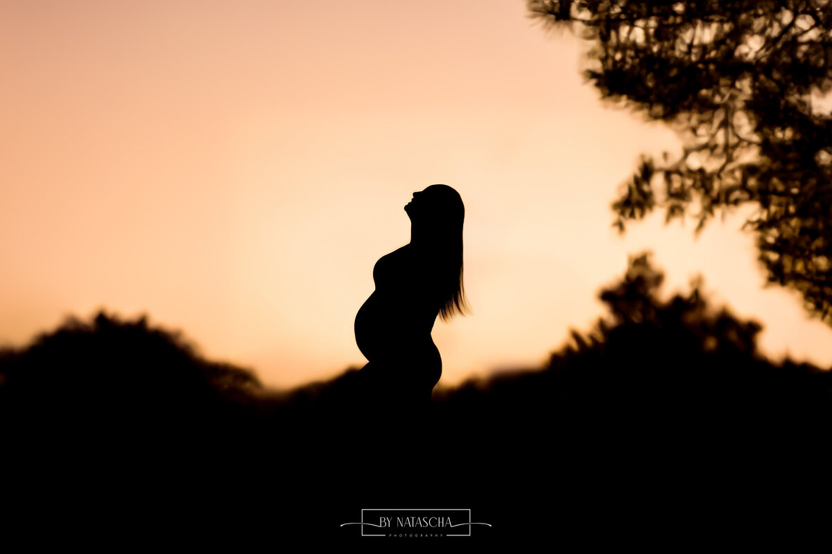 Zwangere vrouw in de duinen met silhouet foto en zonsondergang op de achtergrond