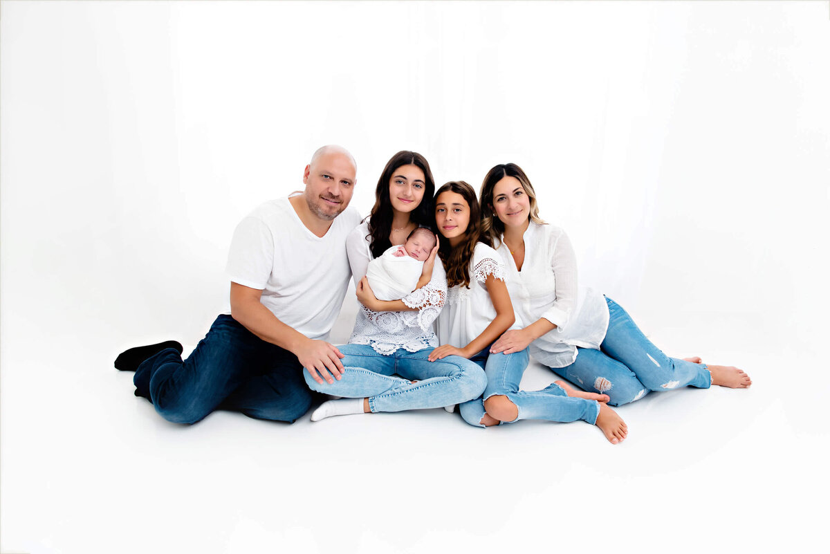 Family of five with their newborn baby boy on a white background for their family newborn photography session in Burlington, Ontario